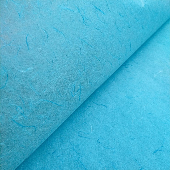 Close-up photograph of Atoll Blue mulberry paper by Kozo Studio, emphasizing the handmade paper texture and natural mulberry fibers.