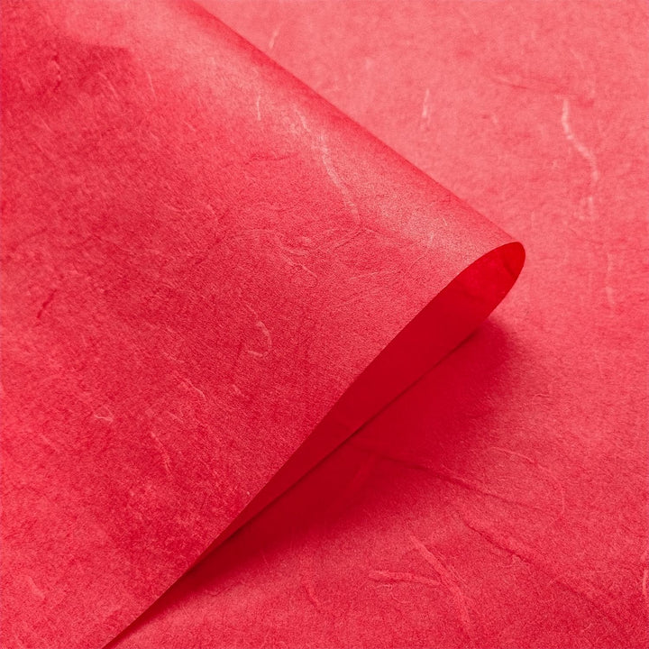 Kozo Studio cherry red handmade paper featuring swirling mulberry fibers and soft diagonal lines in a close-up shot.