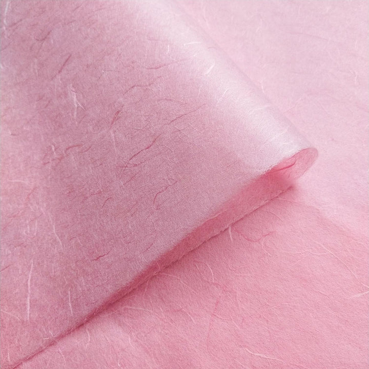 Kozo Studio mulberry paper in Classic Pink folded diagonally to emphasize the fine handmade paper grain and fiber.