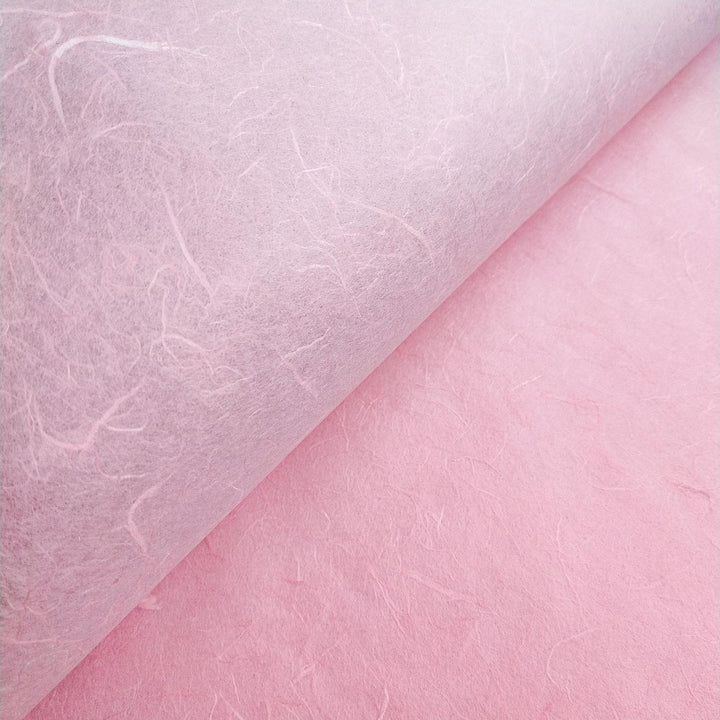 Textured view of Kozo Studio Unryu handmade paper in soft pink, showcasing mulberry fiber patterns.