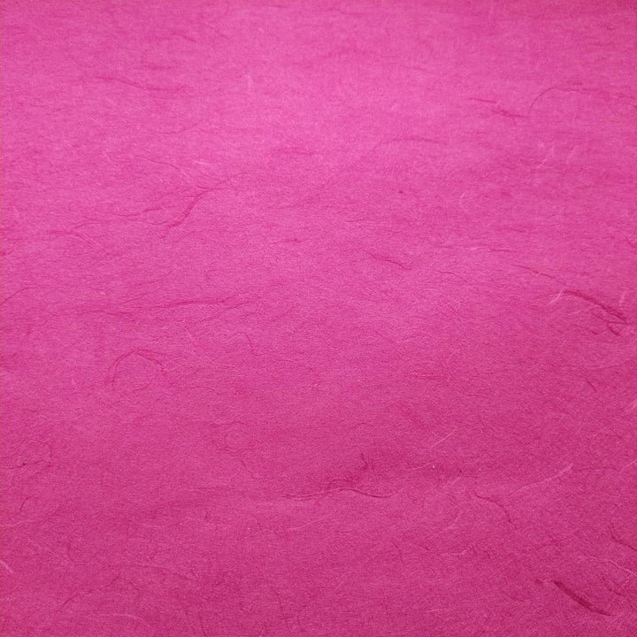 Handmade paper in fuchsia color by Kozo Studio showing intricate Unryu texture and natural mulberry fibers in a folded composition.
