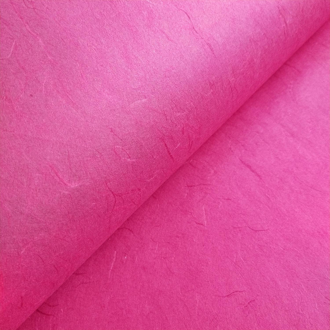 Textured mulberry paper from Kozo Studio in fuchsia, partially folded to highlight its handmade quality and layered depth.
