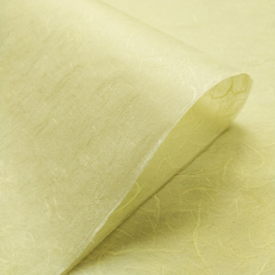 Textured view of lemon yellow handmade paper crafted from mulberry fibers, designed by Kozo Studio with visible natural patterns.