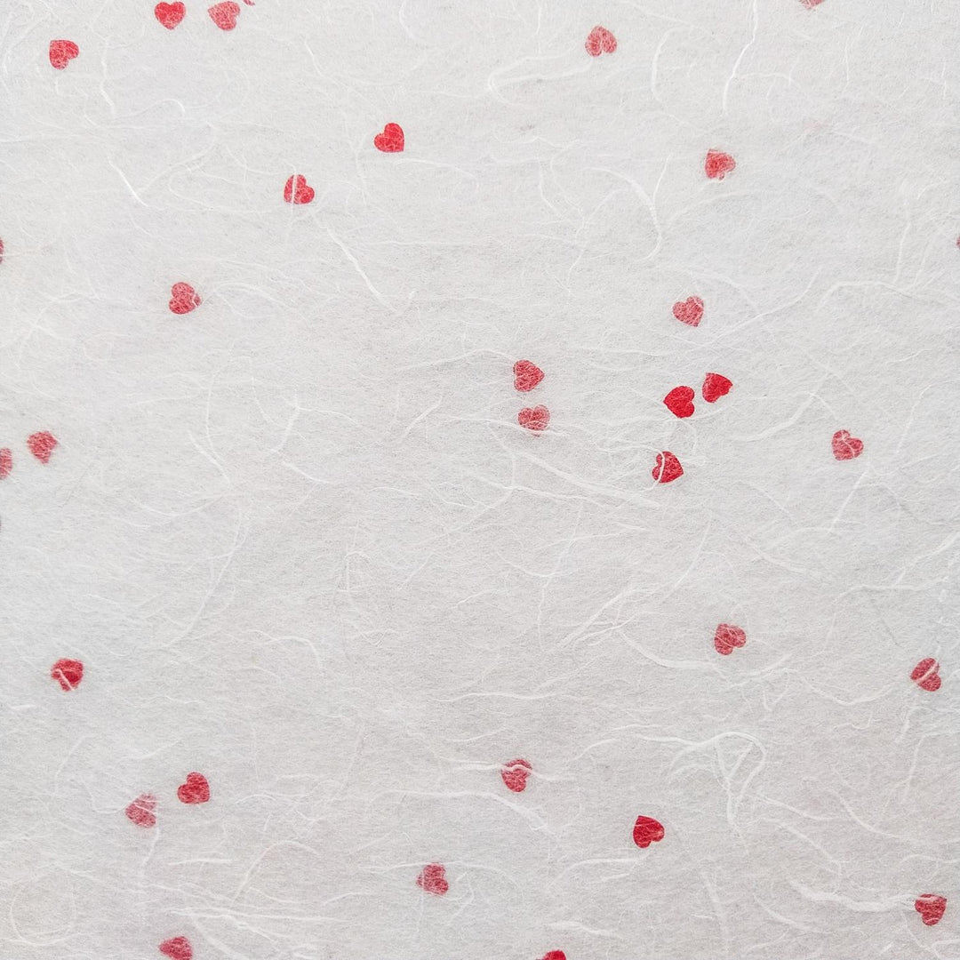 Textured mulberry paper with tiny red heart patterns created by Kozo Studio, a charming example of artisanal handmade paper.