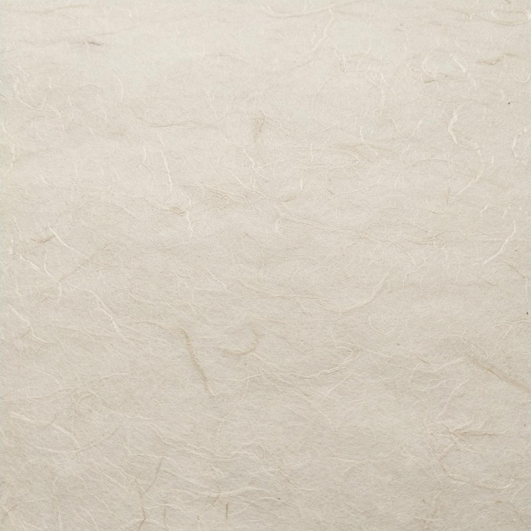Close-up of Kozo Studio handmade paper featuring fibrous strands of mulberry paper on a natural off-white surface.