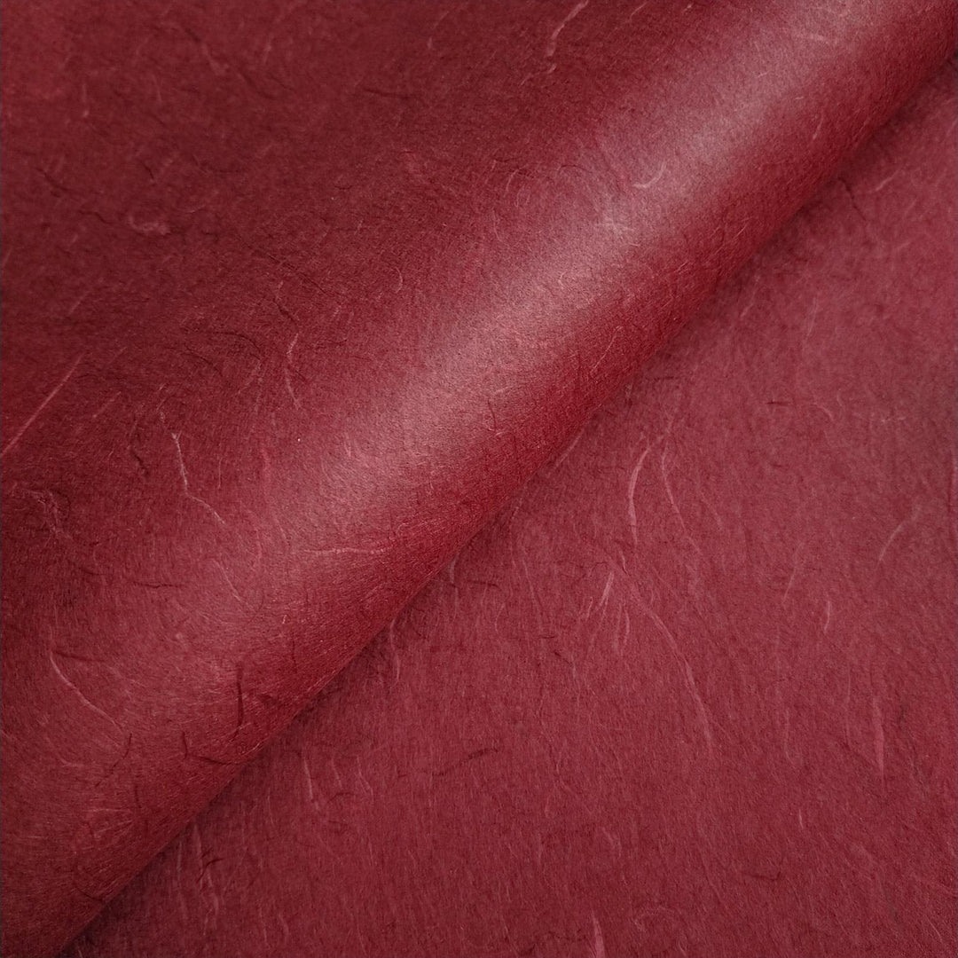 Ruby wine Unryu handmade paper from Kozo Studio displayed in layered diagonals, capturing the organic essence of mulberry paper.