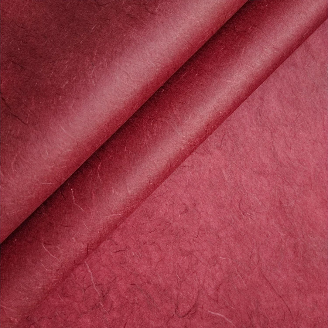 Close-up of Unryu Kozo Paper in ruby wine from Kozo Studio, showing maroon handmade paper with visible fibers and abstract textures similar to mulberry paper.
