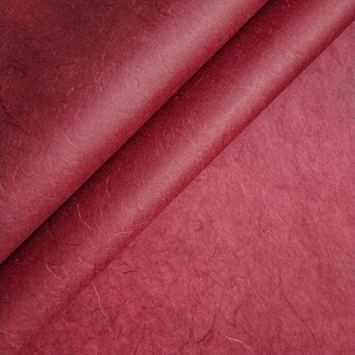 Close-up of Unryu Kozo Paper in ruby wine from Kozo Studio, showing maroon handmade paper with visible fibers and abstract textures similar to mulberry paper.