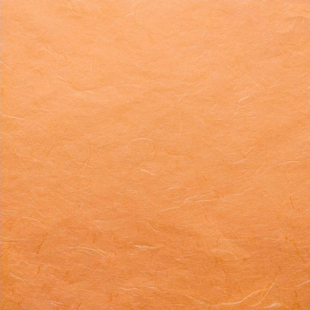 Detailed view of Kozo Studio mulberry paper in vibrant orange, with delicate fibers and rich handmade paper texture.