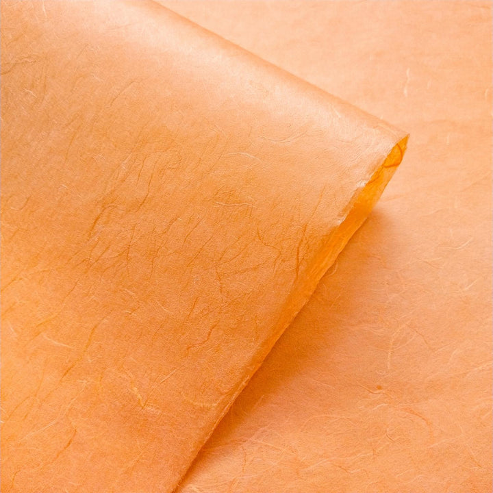 Fibrous surface of Unryu handmade paper in tangerine orange by Kozo Studio, featuring visible strands of mulberry fiber.