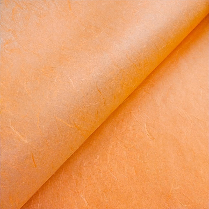 Textured orange mulberry paper crafted by Kozo Studio, showing layered fibers and subtle handmade paper color shifts.