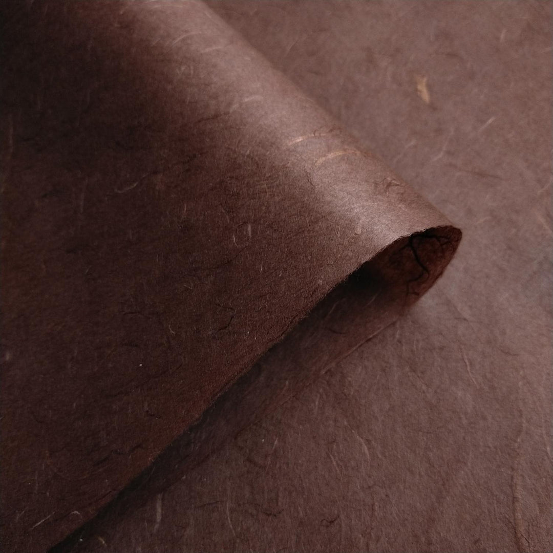 Two sheets of tawny brown Unryu Kozo Studio mulberry paper overlap, showcasing the fibrous handmade paper texture.