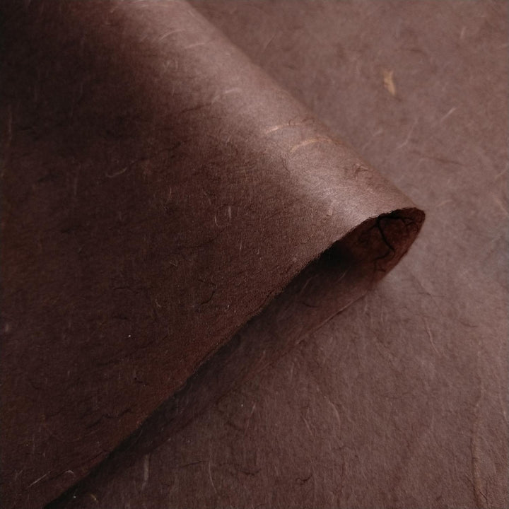 Two sheets of tawny brown Unryu Kozo Studio mulberry paper overlap, showcasing the fibrous handmade paper texture.