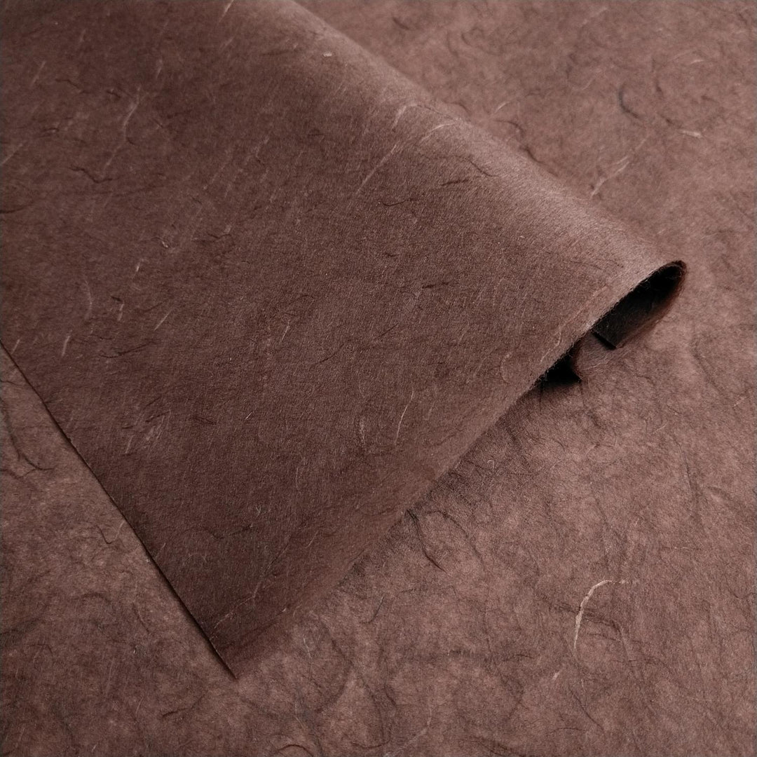 Textured layers of brown handmade paper made from mulberry fibers by Kozo Studio, highlighting the natural surface of Unryu Kozo paper.