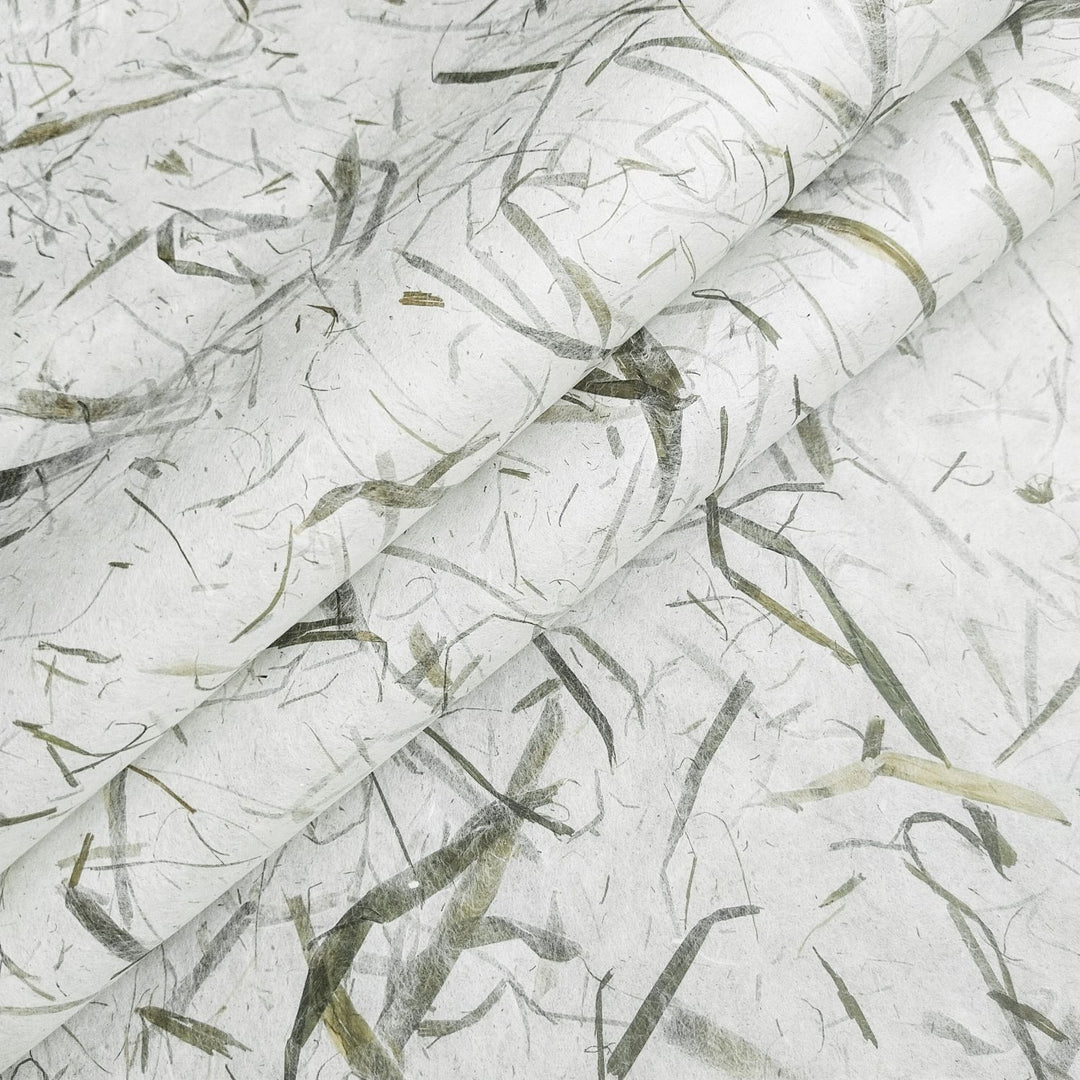 Close-up of Bamboo Leaf Kozo handmade paper from Kozo Studio, showcasing real bamboo leaves embedded in delicate mulberry paper with a soft, organic texture.