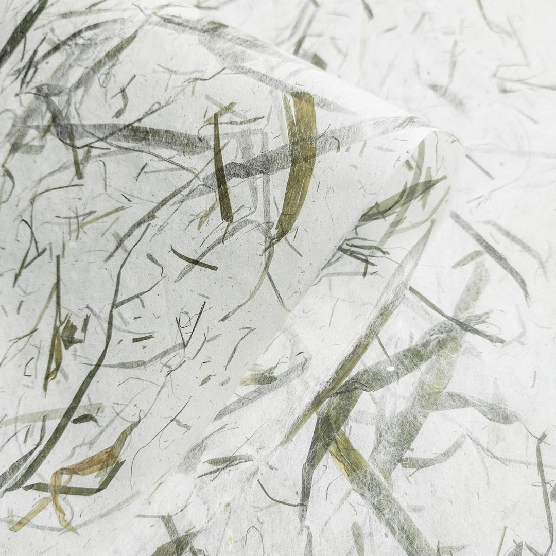 Detailed view of Bamboo Leaf Kozo handmade paper by Kozo Studio, featuring real leaf inclusions and mulberry fibers forming a natural, oriental-inspired design.