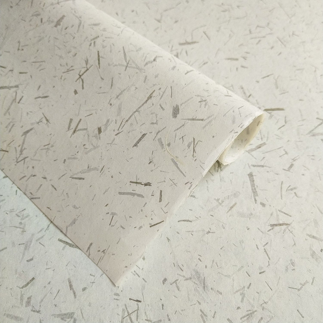 Handmade Bamboo Confetti Kozo paper by Kozo Studio showcasing a unique texture of natural fibers and bamboo leaf flecks, ideal for crafts and home decor.