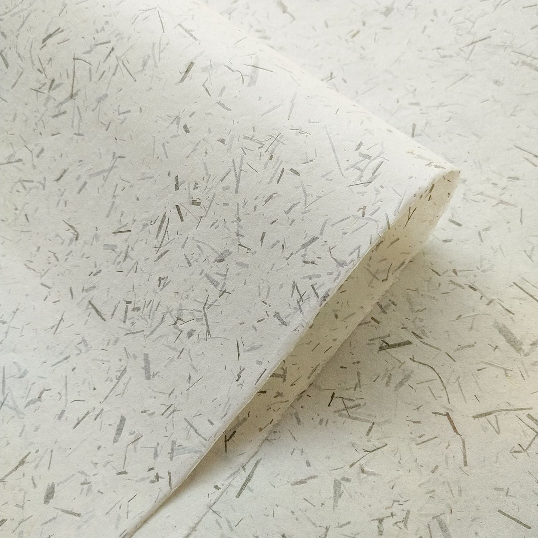 High-resolution shot of semi-translucent mulberry paper from Kozo Studio, featuring bamboo confetti and a natural, eco-friendly handmade finish.