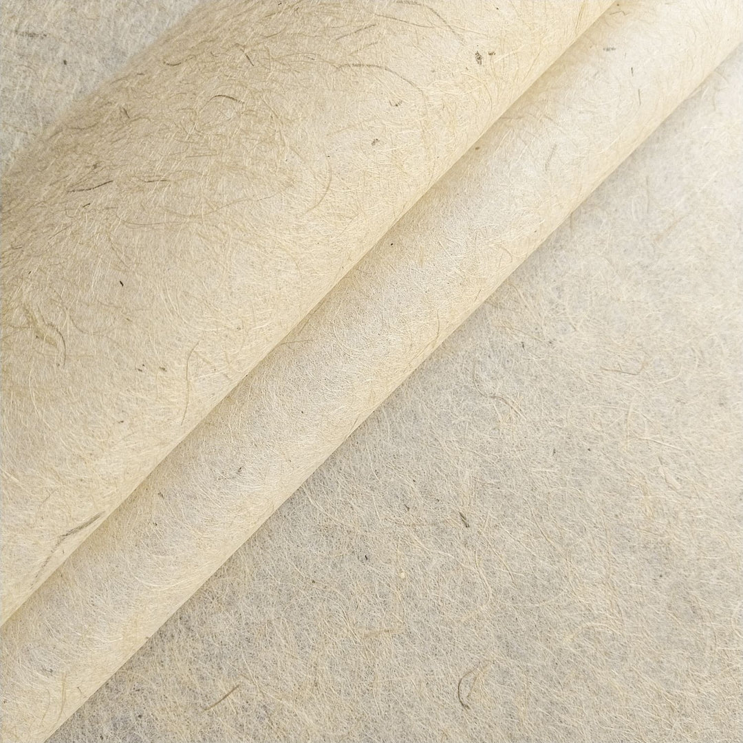 Close-up of Kozo Studio jute and mulberry paper with visible fibers and a curled corner, showcasing the handmade paper's natural texture and flexibility.