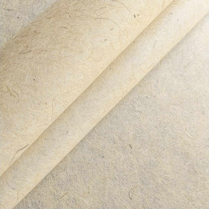 Close-up of Kozo Studio jute and mulberry paper with visible fibers and a curled corner, showcasing the handmade paper's natural texture and flexibility.