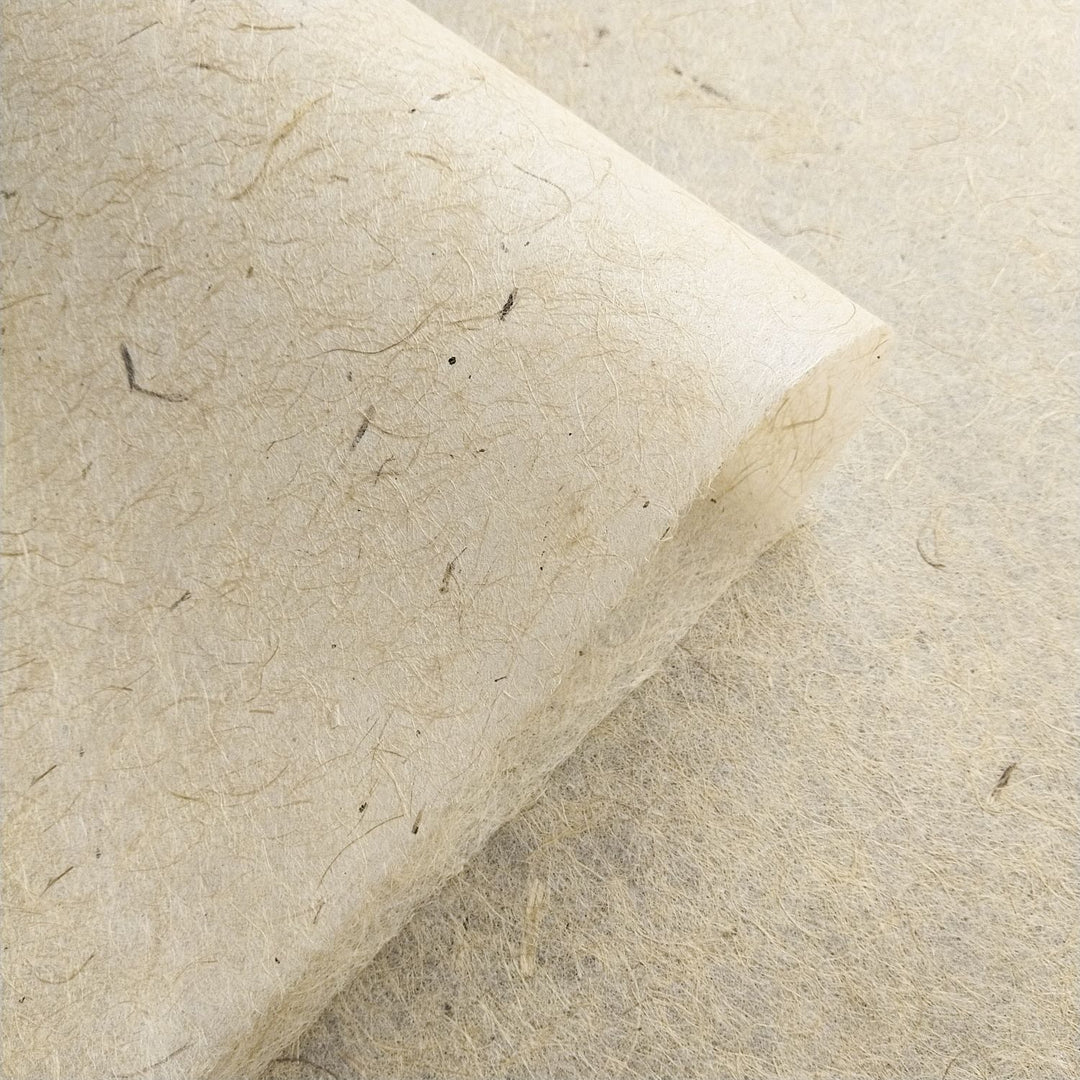 Kozo Studio close-up of handmade jute and mulberry paper with a curled edge and visible natural fibers, emphasizing its use in versatile art applications.