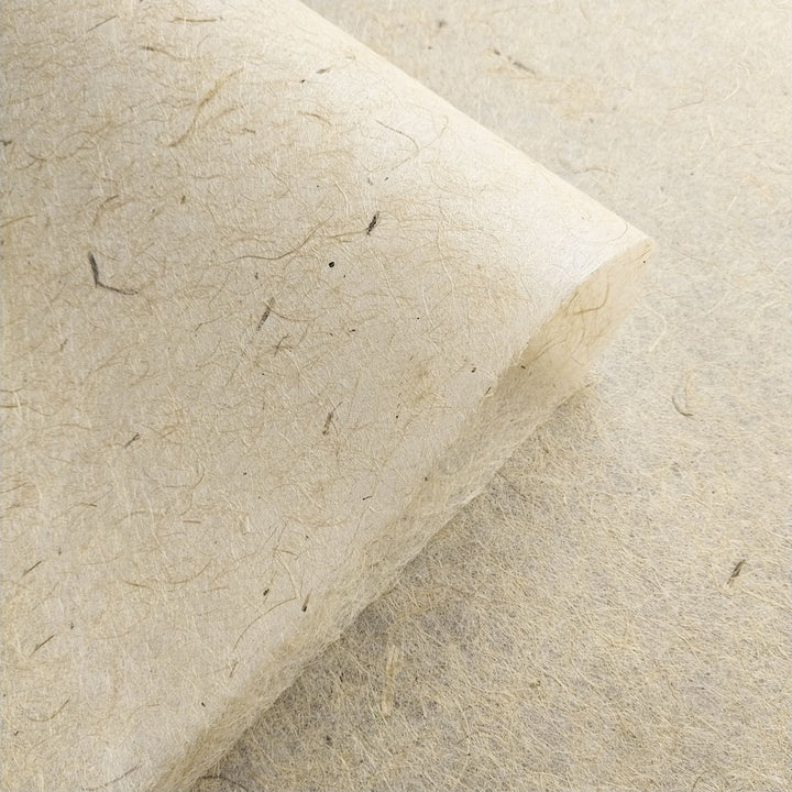 Kozo Studio close-up of handmade jute and mulberry paper with a curled edge and visible natural fibers, emphasizing its use in versatile art applications.
