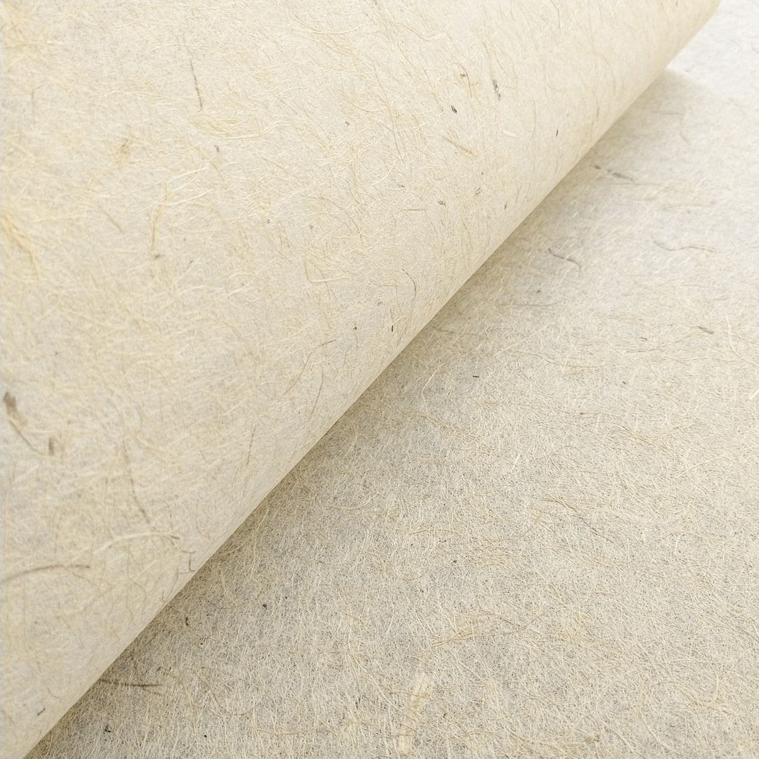 Artistic photograph of handmade paper by Kozo Studio made from jute and mulberry pulp, showing a fibrous texture and subtle brown tone ideal for crafts.