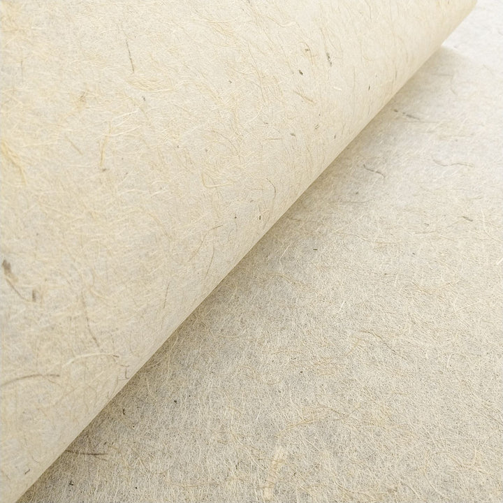 Artistic photograph of handmade paper by Kozo Studio made from jute and mulberry pulp, showing a fibrous texture and subtle brown tone ideal for crafts.