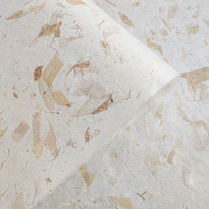 Eco-friendly handmade mulberry paper with mango leaf inclusions by Kozo Studio, emphasizing its tropical texture, beige hues, and strong yet delicate form.