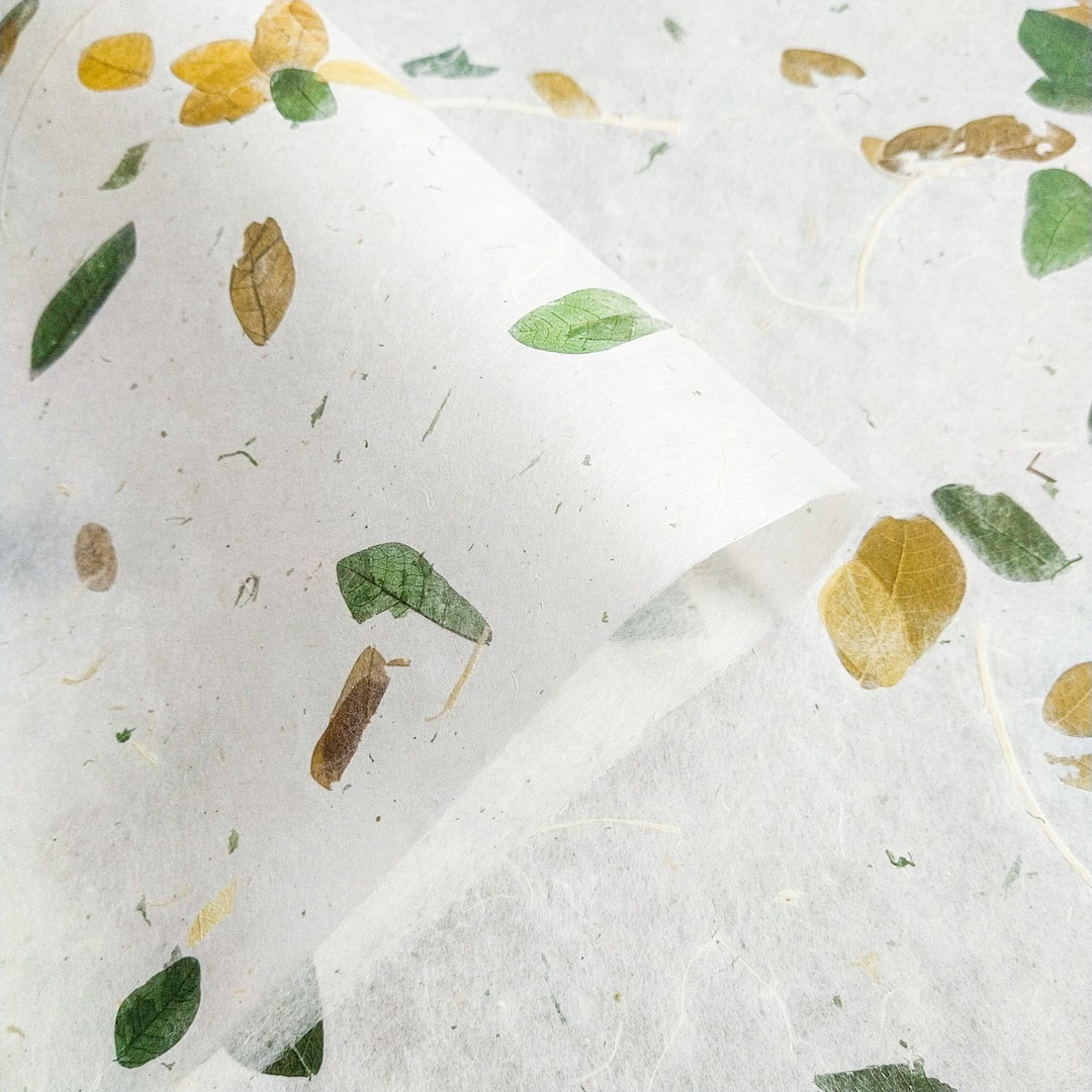 Close-up of Kozo Studio’s Raintree Kozo, a handmade paper with embedded tropical leaves, highlighting the elegance and strength of mulberry paper design.