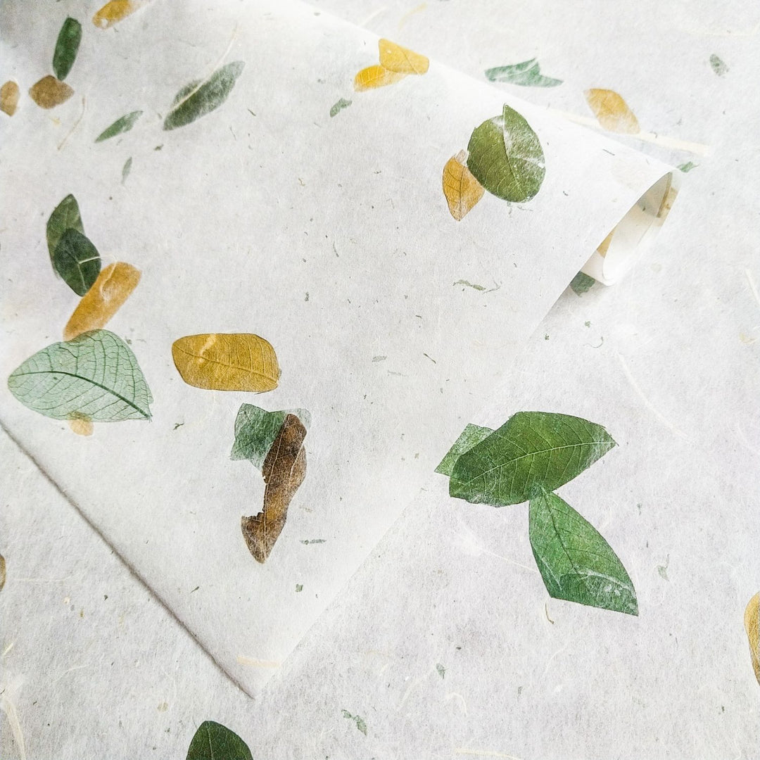 Artistic shot of Raintree Kozo paper from Kozo Studio, featuring a semi-transparent mulberry paper base with leaf accents in green and yellow hues.