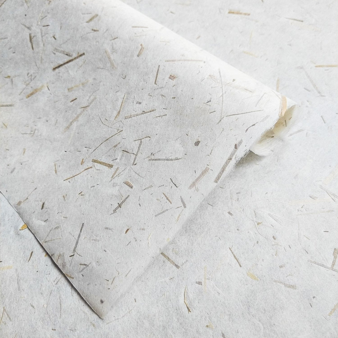 Eco-conscious mulberry paper infused with rice straw confetti, made by Kozo Studio, highlighting the strength and beauty of handmade paper.