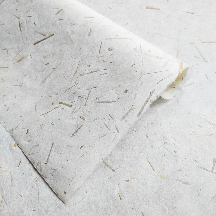 Eco-conscious mulberry paper infused with rice straw confetti, made by Kozo Studio, highlighting the strength and beauty of handmade paper.