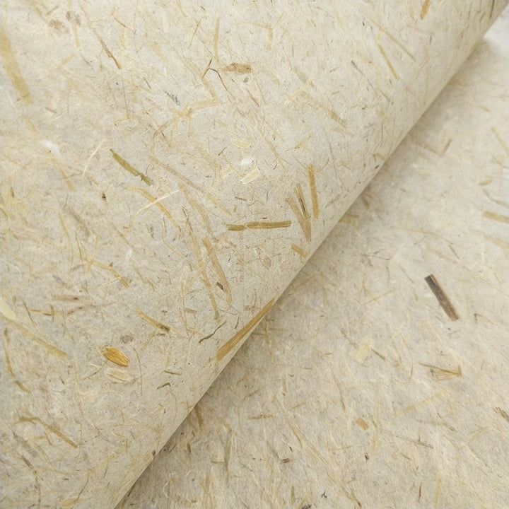 Organic-looking handmade paper by Kozo Studio, made with mulberry fibers and decorated with straw inclusions for a natural, eco-friendly appearance.