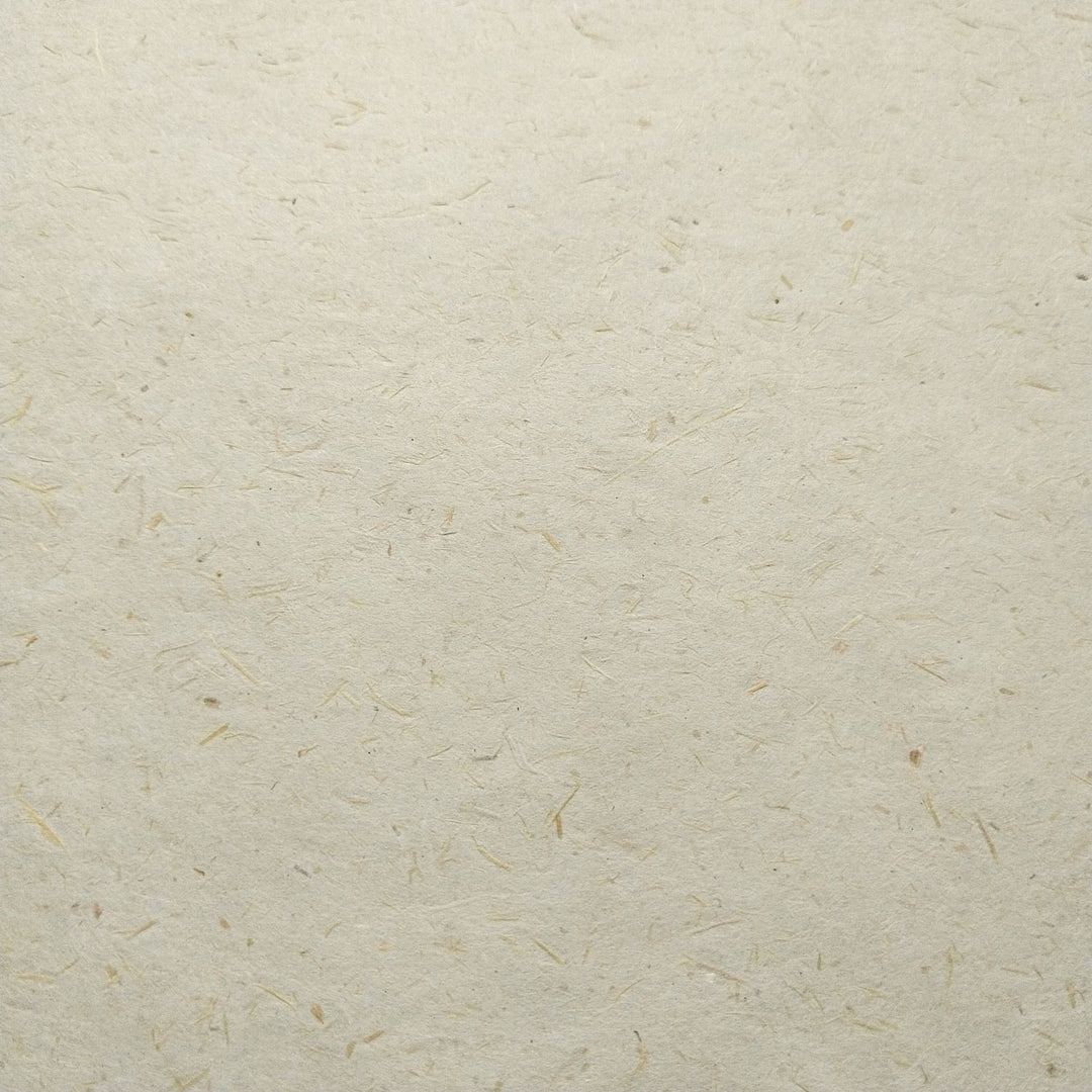 Creamy-toned mulberry paper from Kozo Studio shown in a close-up fold, revealing unique fiber patterns from sugarcane and kozo blend.