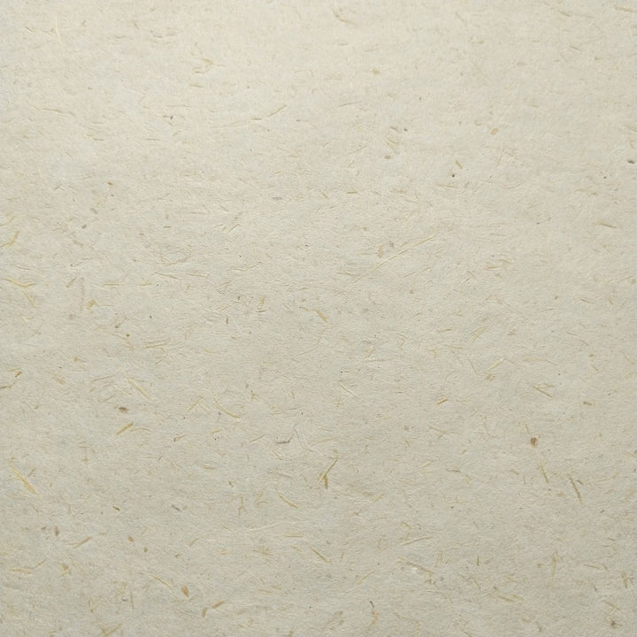 Creamy-toned mulberry paper from Kozo Studio shown in a close-up fold, revealing unique fiber patterns from sugarcane and kozo blend.