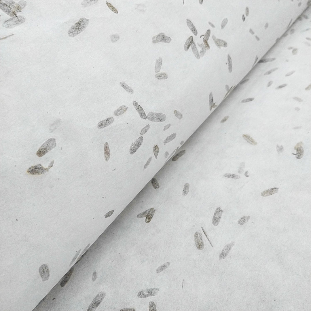 Artistic close-up of Kozo Studio handmade paper, made from mulberry fibers with visible tamarind leaf inclusions and subtle earthy specks.