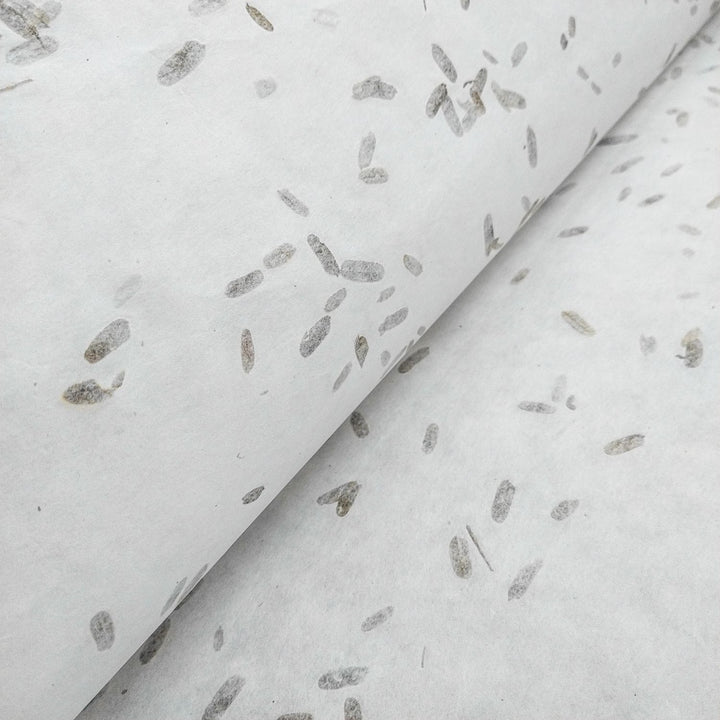 Artistic close-up of Kozo Studio handmade paper, made from mulberry fibers with visible tamarind leaf inclusions and subtle earthy specks.