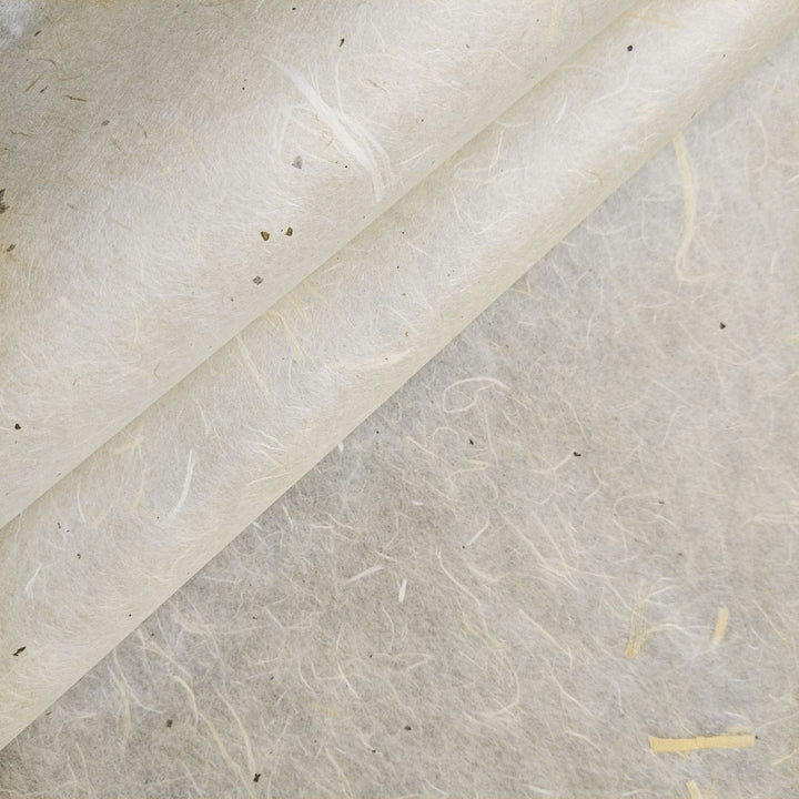 A close-up of Kozo Studios Unryu Kozo Paper with Mulberry Bark reveals its textured surface with visible fibers and small speckles. This handmade paper features a natural, off-white color, subtle variations, and a slightly rough texture for a soft, organic appearance enhanced by light and shadows.