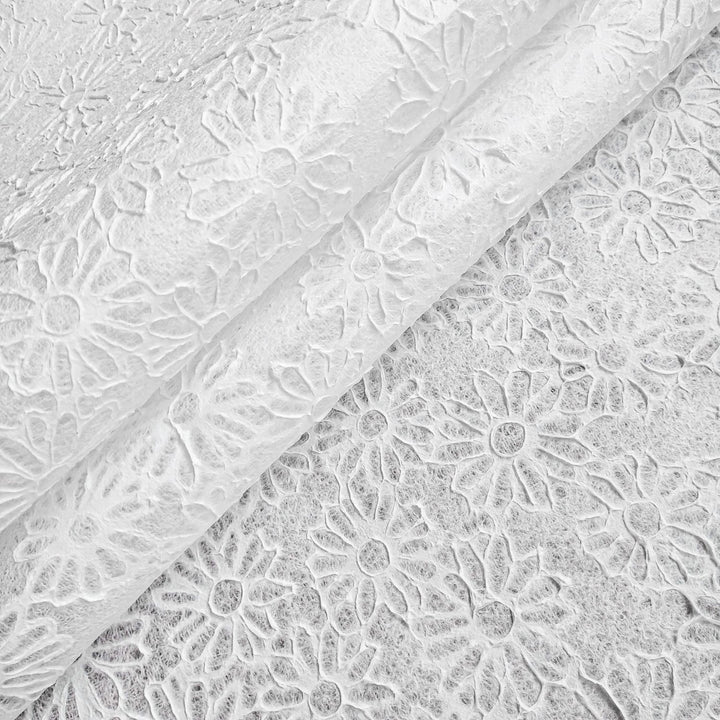Close-up of Handmade Embossed Lace Kozo Paper by Kozo Studio in white, showcasing a textured floral pattern with daisy-like flowers. Two overlapping mulberry sheets are visible, featuring detailed relief designs.
