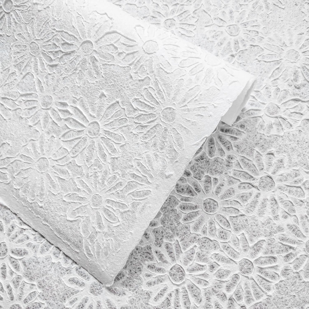 Embossed daisy-patterned mulberry paper from Kozo Studio, showcasing the Rakusui water-drop technique for a translucent handmade paper ideal for crafts and decor.