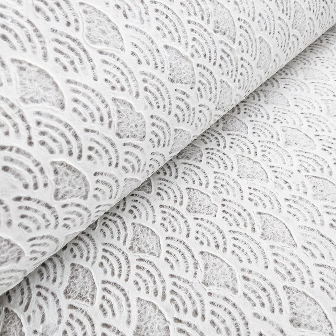 Handmade Lace Kozo Paper (Fan) by Kozo Studio offers rolls of textured white Mulberry paper with a fan pattern. The design features a detailed and intricate look with its slightly raised texture.