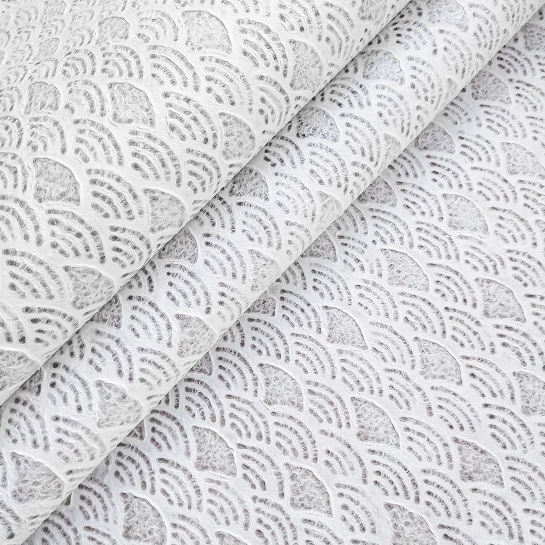 A close-up of Handmade Lace Kozo Mulberry Paper (Fan) from Kozo Studio reveals an intricate fan pattern, resembling overlapping seashells, creating a layered, three-dimensional effect with shadowed depth.