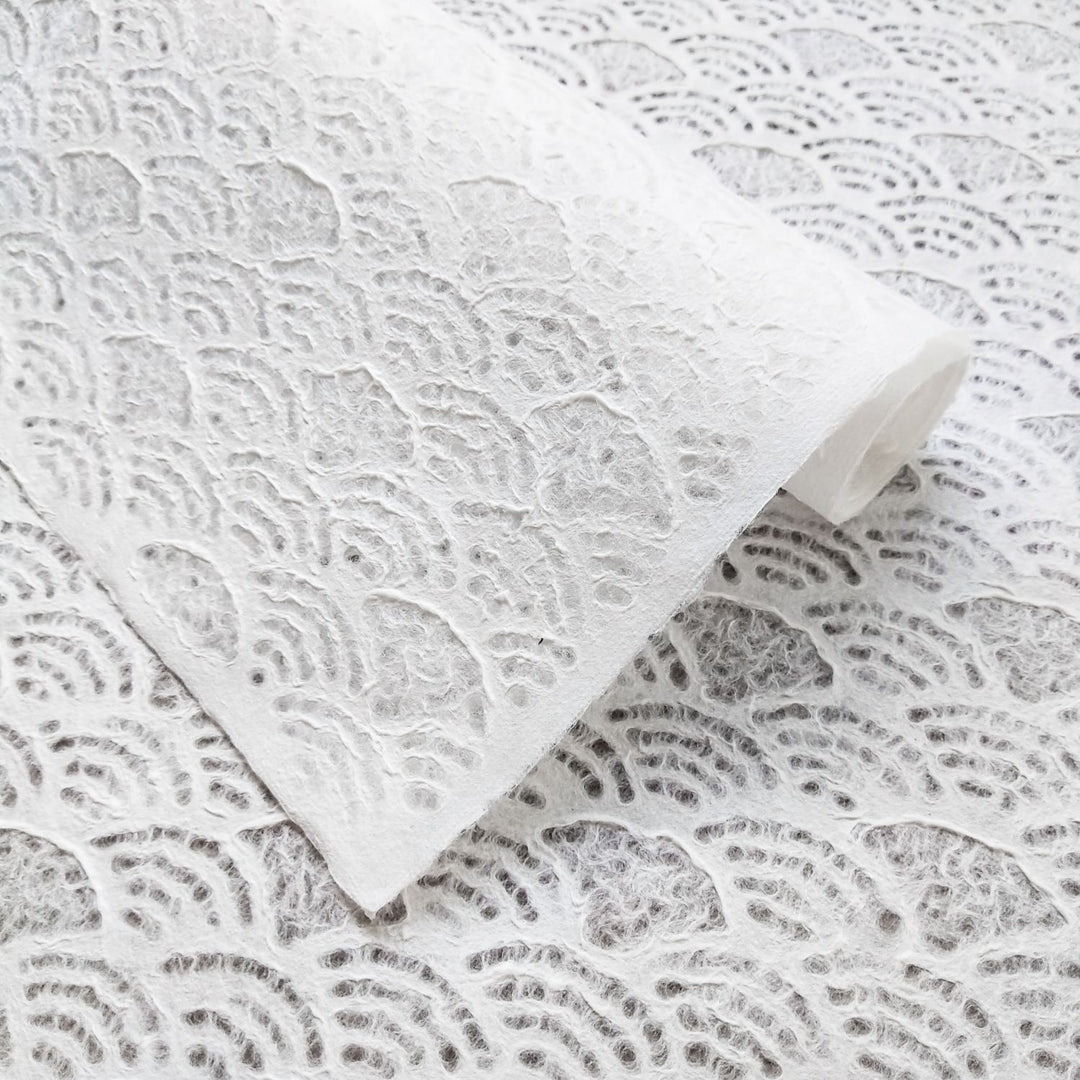 Close-up of Handmade Lace Kozo Mulberry Paper (Fan) by Kozo Studio, featuring a textured, white surface with swirling, scalloped designs. It showcases soft layers and delicate, artistic craftsmanship.