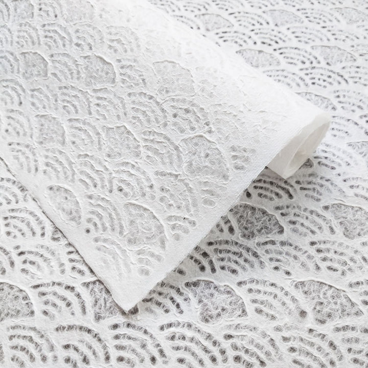 Close-up of Handmade Lace Kozo Mulberry Paper (Fan) by Kozo Studio, featuring a textured, white surface with swirling, scalloped designs. It showcases soft layers and delicate, artistic craftsmanship.