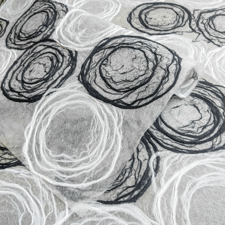 Artistic rose-patterned mulberry paper from Kozo Studio, made with hand-drawn pulp circles, perfect for elegant decor and crafts.