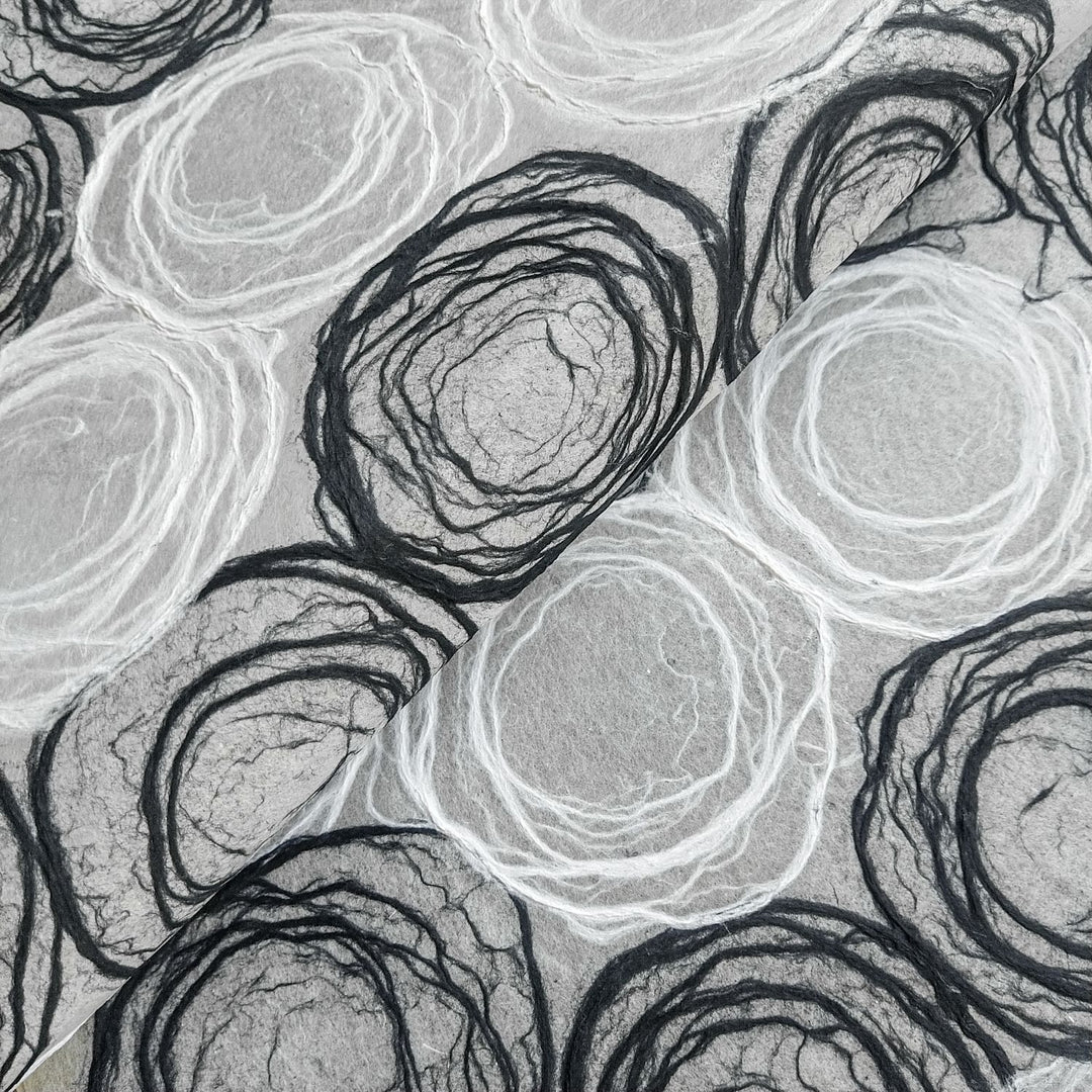 Handmade mulberry paper by Kozo Studio featuring intricate black and white circular rose patterns, ideal for lamp shades and art projects.