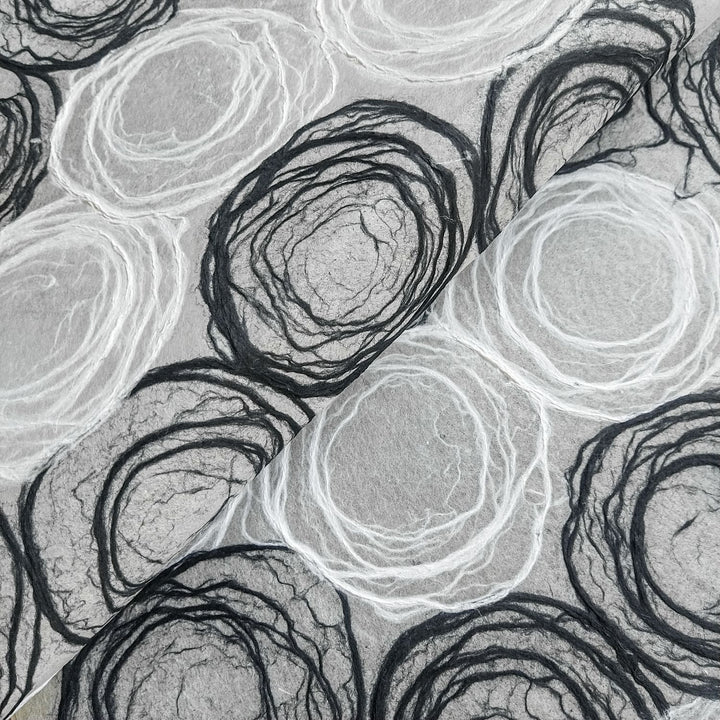 Handmade mulberry paper by Kozo Studio featuring intricate black and white circular rose patterns, ideal for lamp shades and art projects.