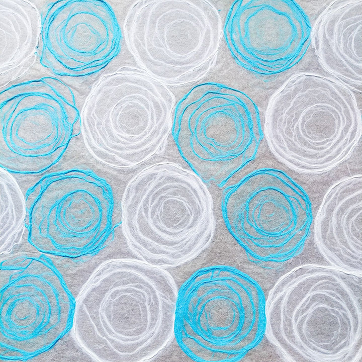 Kozo Studio's handmade paper featuring circular pulp textures on a light blue and white mulberry base, designed for lampshades, windows, and fine art.