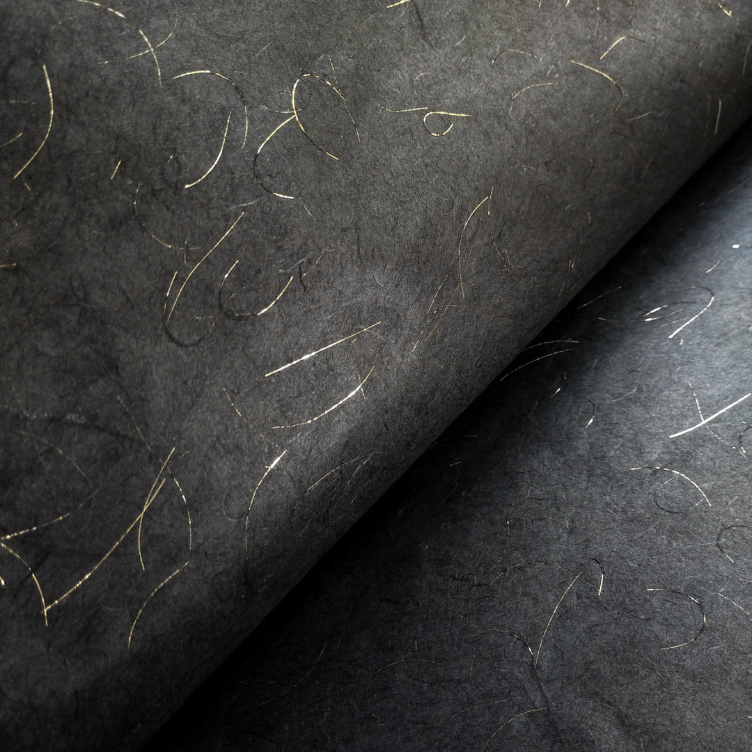 Artistic close-up of Kozo Studio Golden Tinsel Unryu paper, a luxurious handmade mulberry paper with black tones and thin, metallic gold threads.
